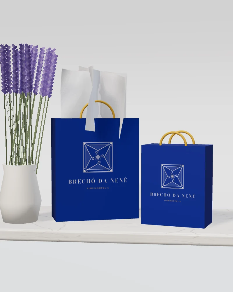 Sacolas azuis do Brechó da Nenê com o ladrilho da marca e papel de seda, ao lado de um vaso de lavanda