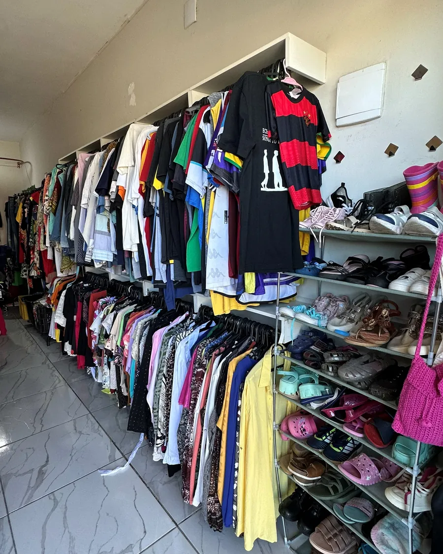 Camisetas na arara e a sapateira cheia de calçados