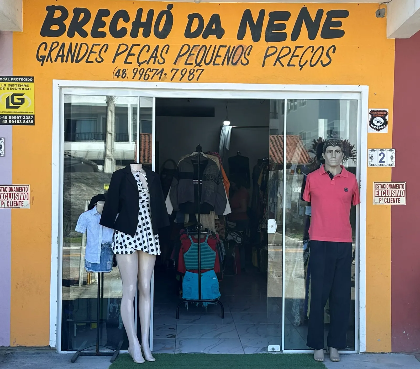Fachada do Brechó da Nenê: parede laranja com o nome pintado, porta de vidro e manequins na calçada